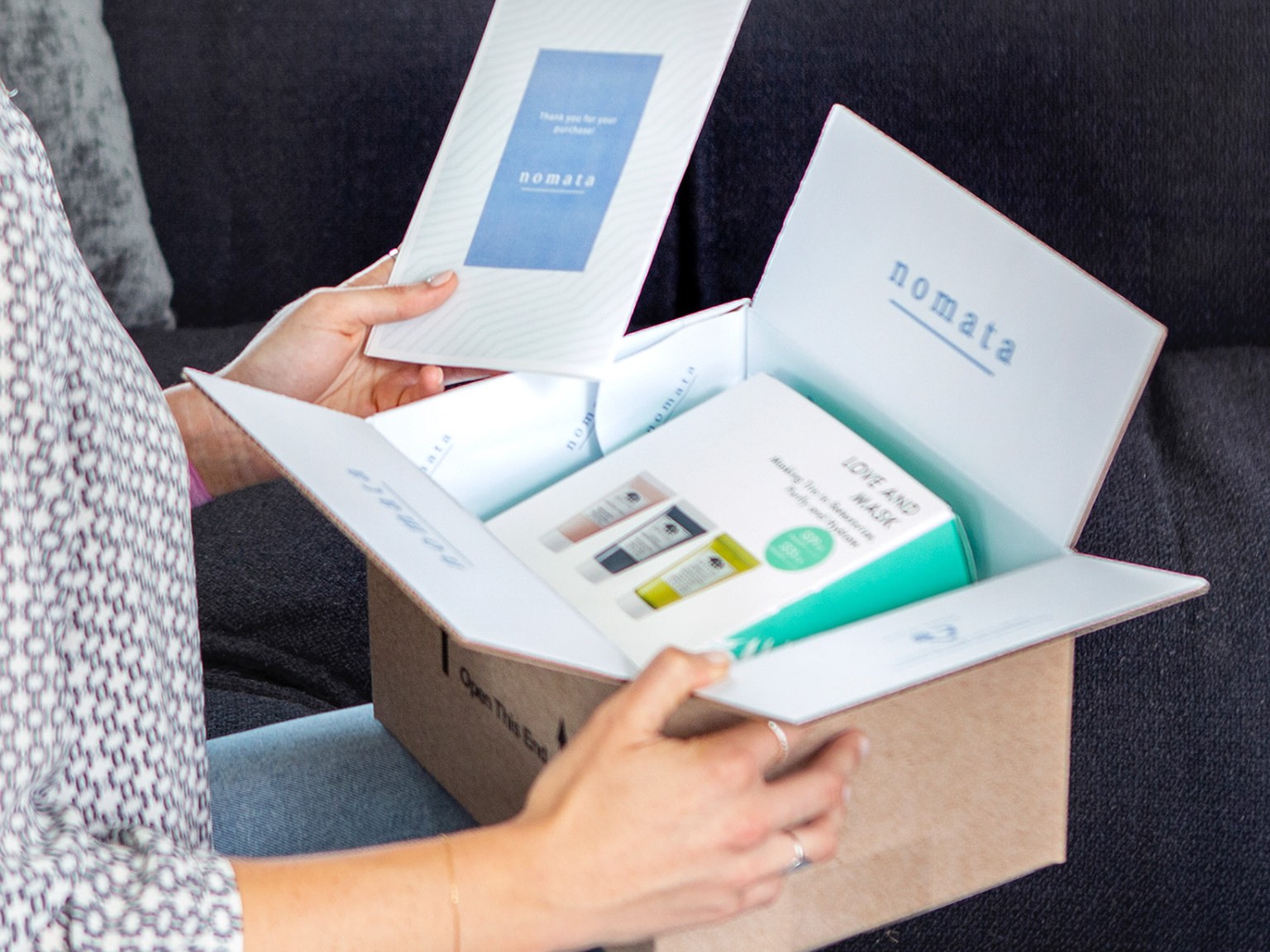 An open kraft mailer showing printed interior branding, a thank-you card and packaged products