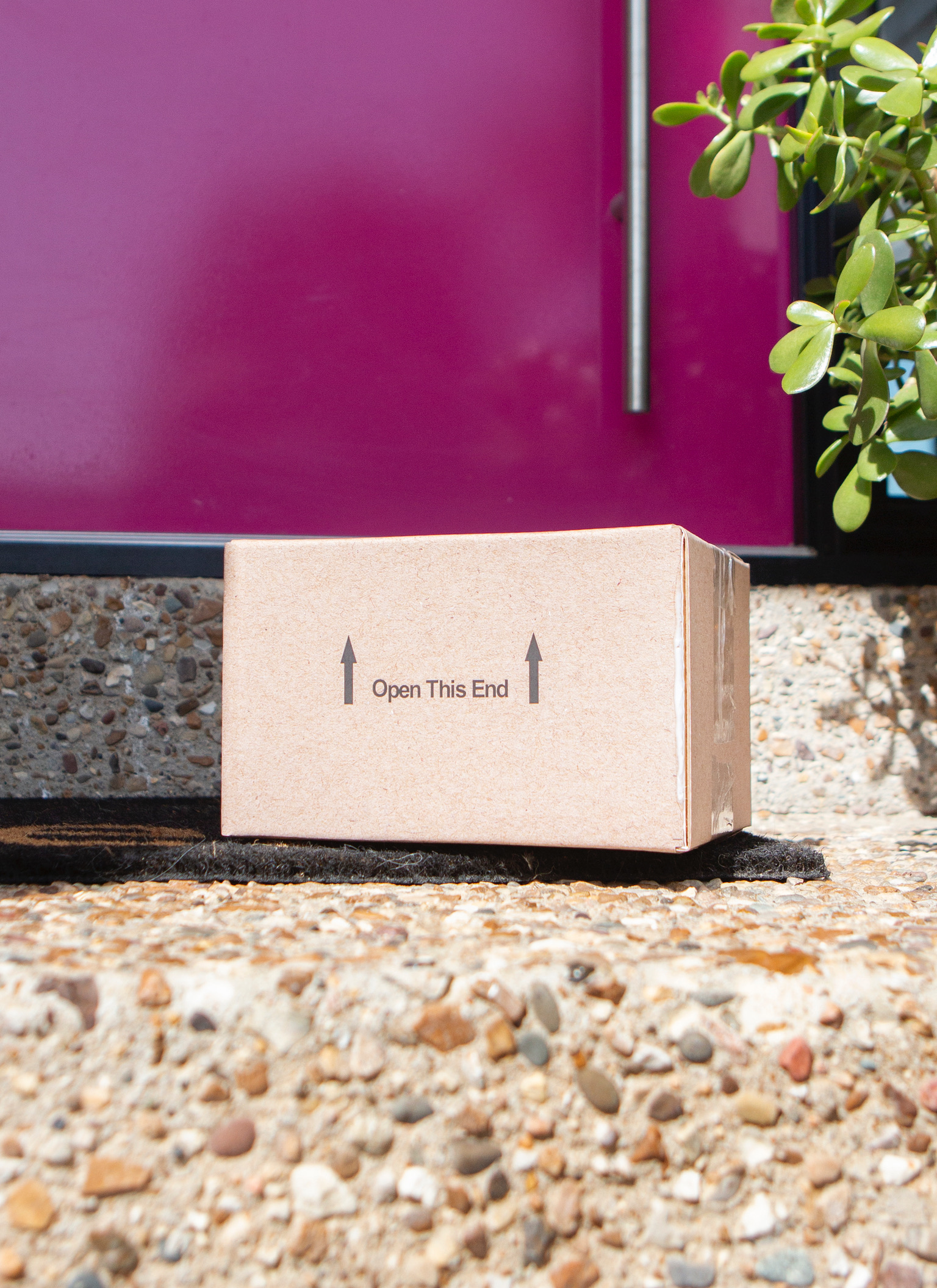 A delivered cardboard parcel outside a pink front door